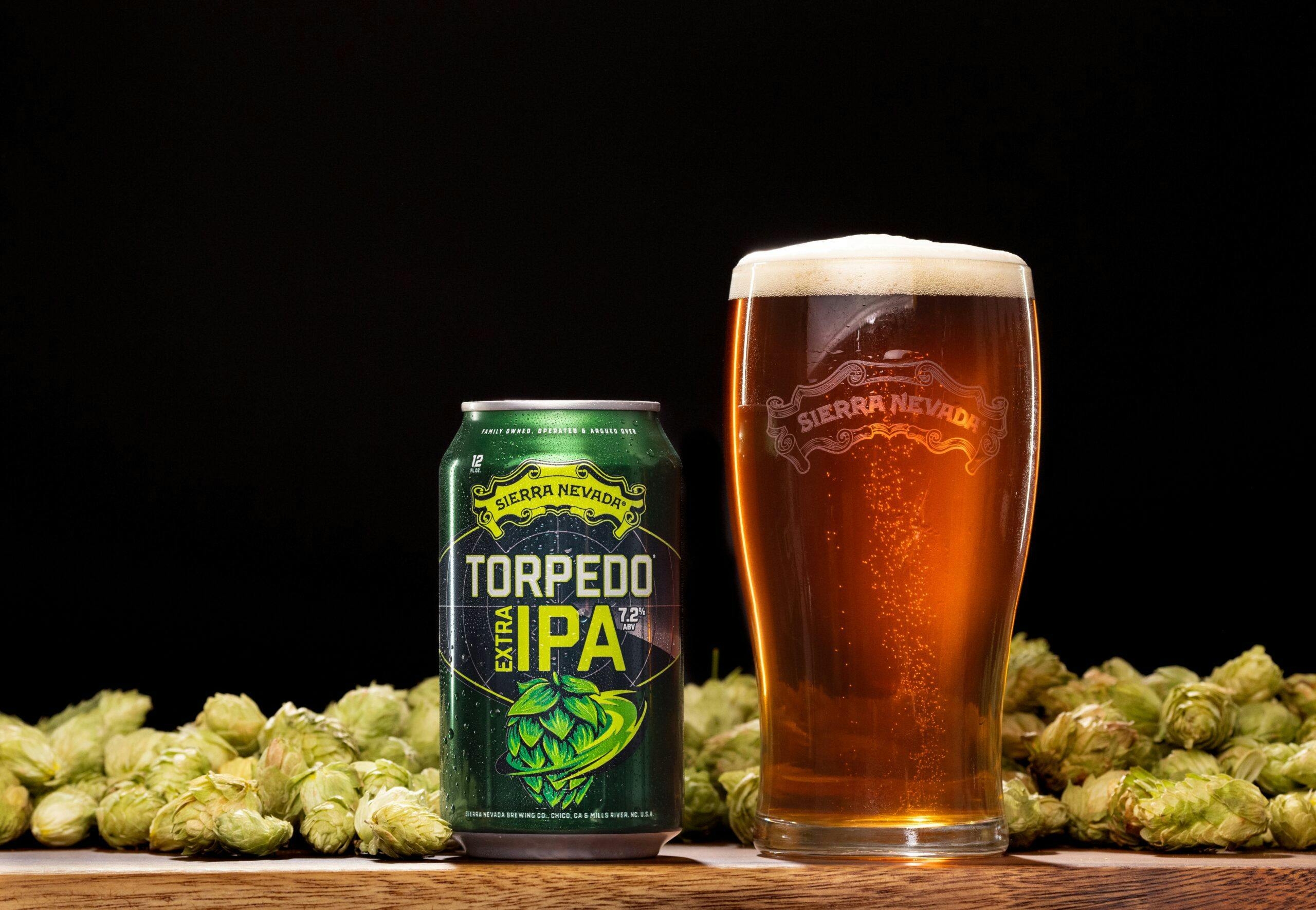 Torpedo Extra IPA can and glass on table in front of hops