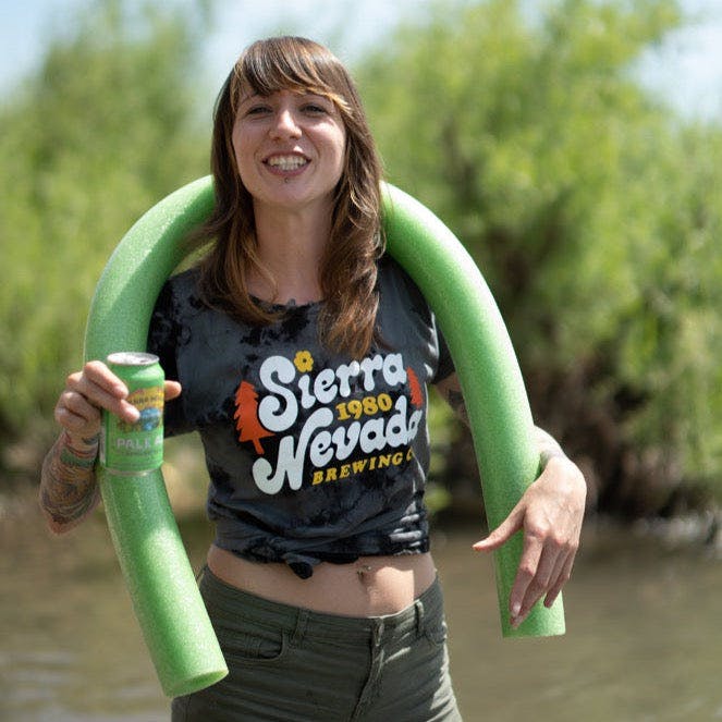 A woman wears the Sierra Nevada Brewing Co. Acid Washed Retro T-Shirt during a tubing adventure on a river.